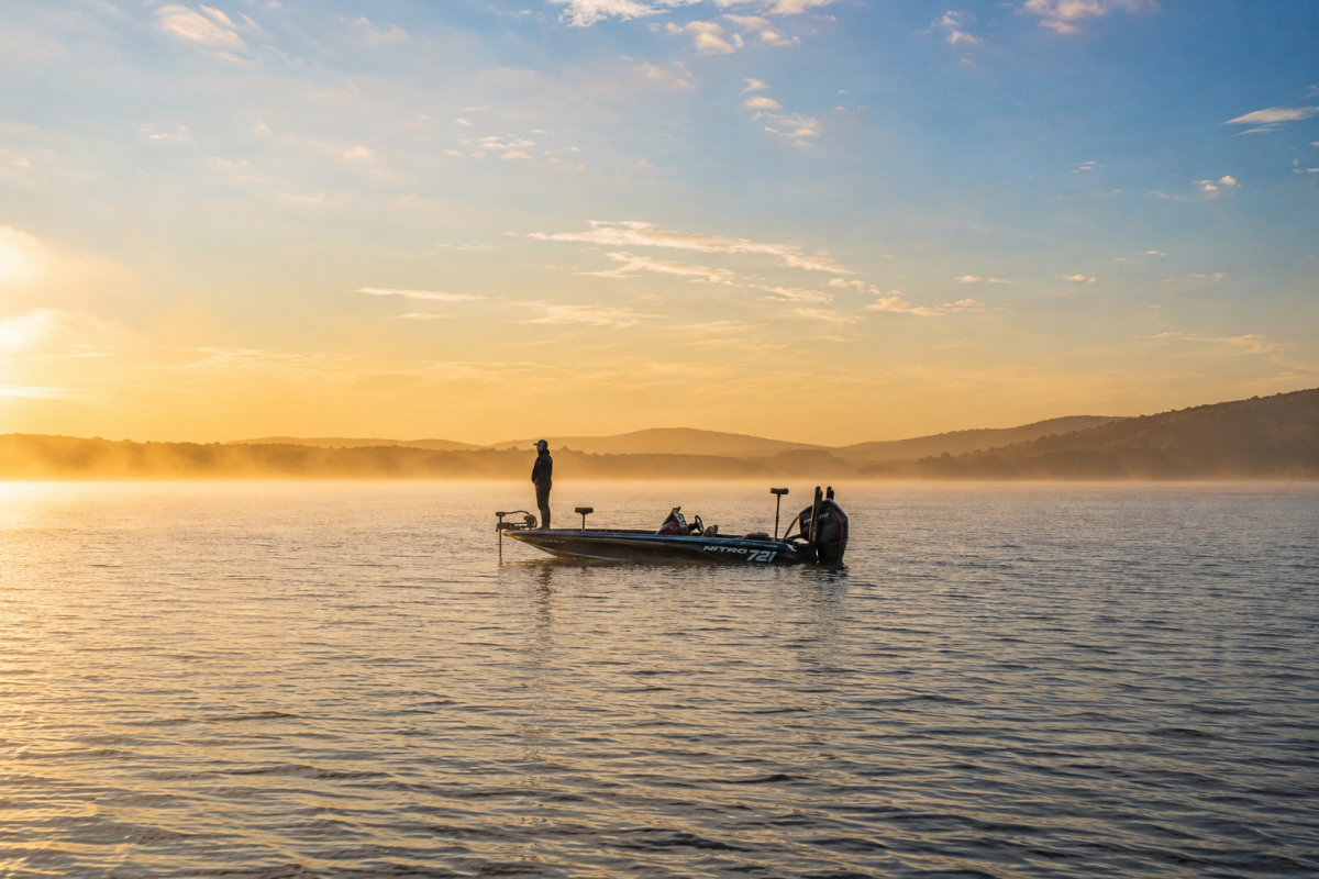 Angler fishing from a bass boat at sunrise as part of a newport vs minn kota trolling motors comparison