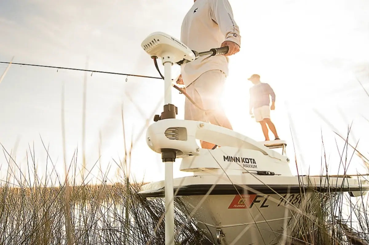 Two fishermen standing on a boat, using a saltwater trolling motor in freshwater.