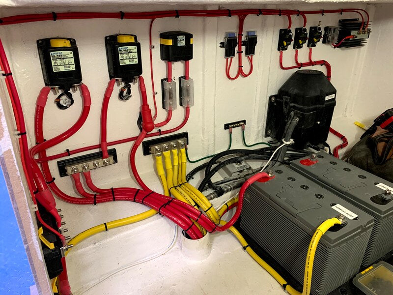 A well-organized marine electrical system featuring neatly routed red and yellow wiring, battery terminals, fuse panels, and circuit breakers inside a boat. Proper cable management and corrosion prevention ensure optimal electrical performance and safety.
